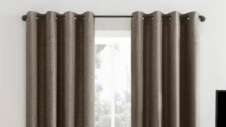 Sun Zero Pratt tonal texture fleece insulated blackout curtains cover a window next to a lamp