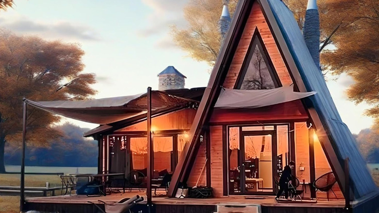 The A-frame tiny home cottage illuminated in the forest.