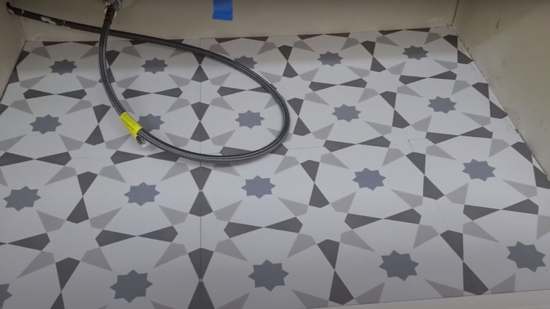 Patterned white and gray vinyl tiles inside cabinet on floor