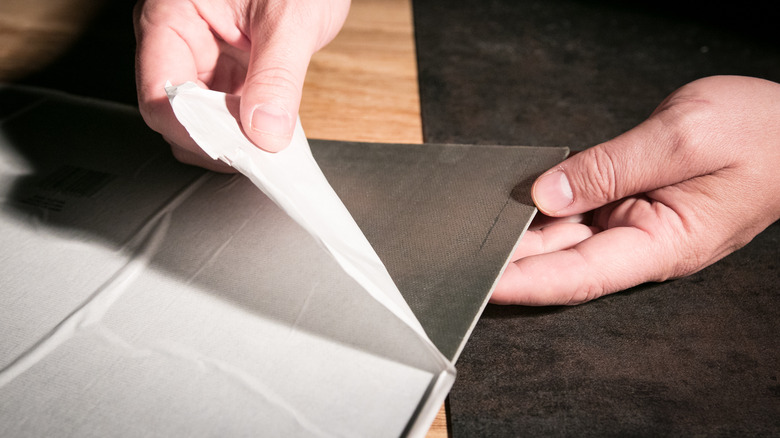 man peeling vinyl tile