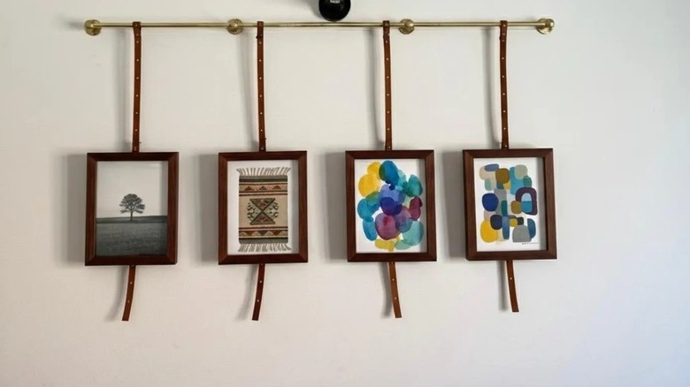 A brass gallery rail with photos and imagery hanging from it.