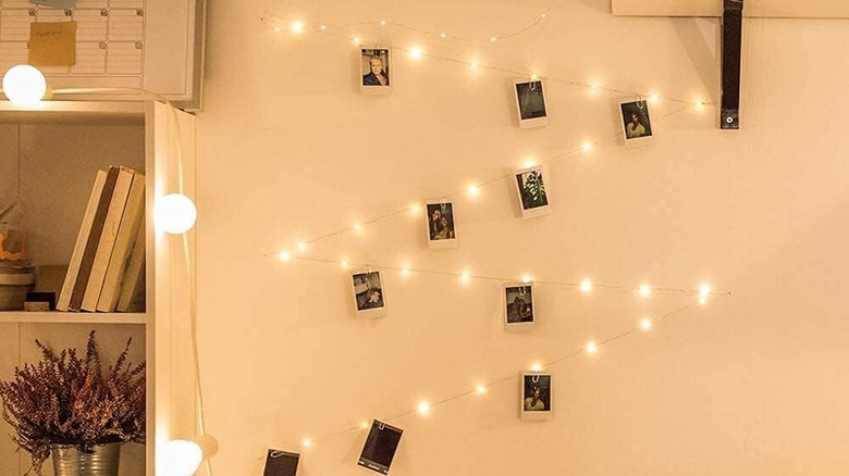 Rows of photos attached the the wall with a row of string lights combined with clothes pegs.
