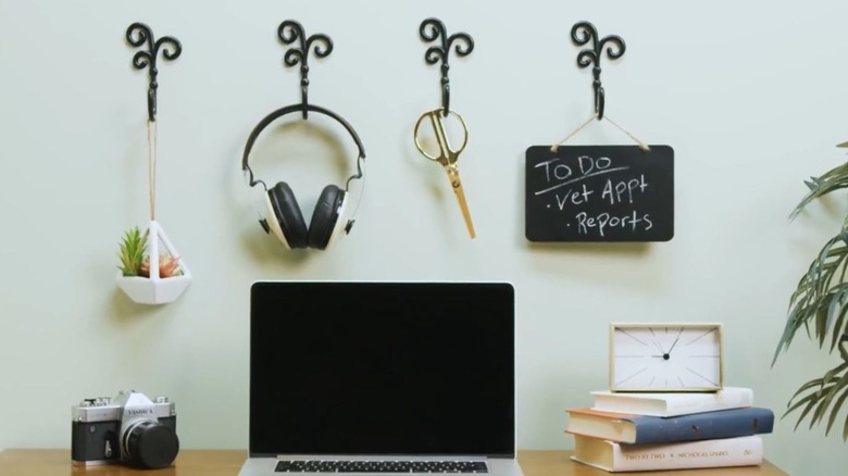 Curtain tie backs hold a plant, headphones, scissors, and a chalk board above a home office desk