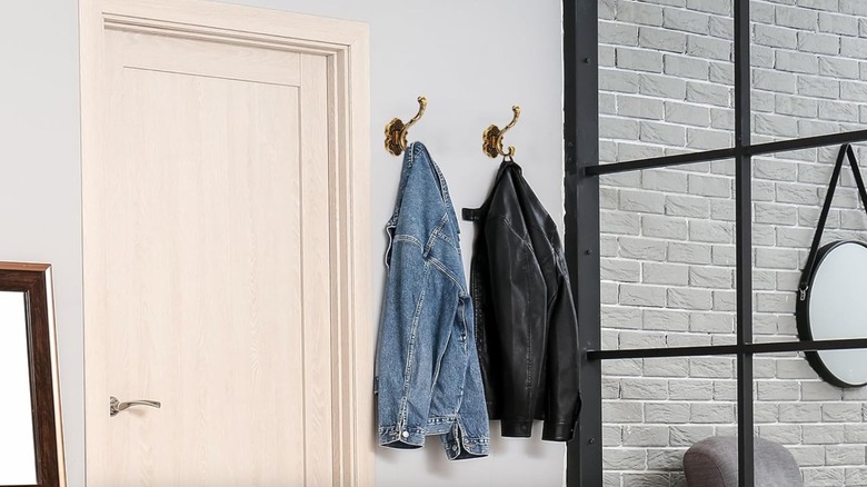 Two jackets hanging on ornate hooks in an entryway