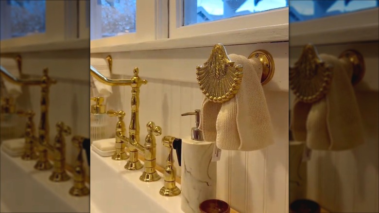 An ornate curtain tie-back holds a kitchen towel by the sink
