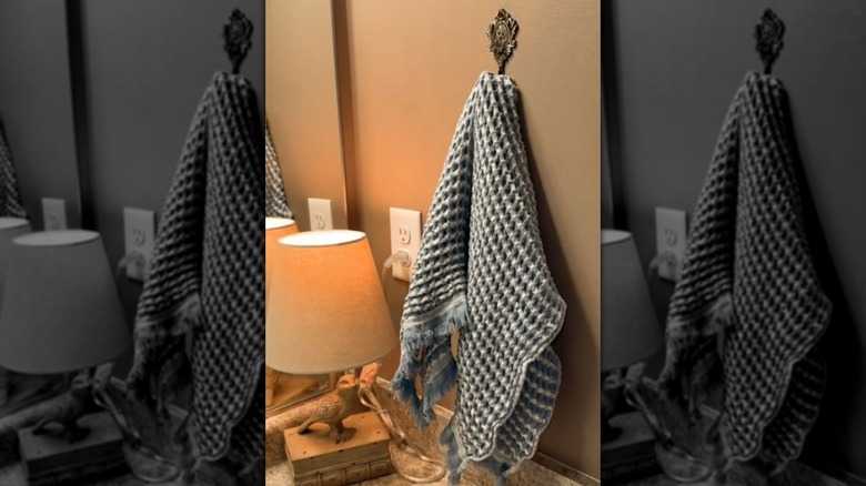 A hand towel rests on an ornate curtain tie back by the bathroom counter