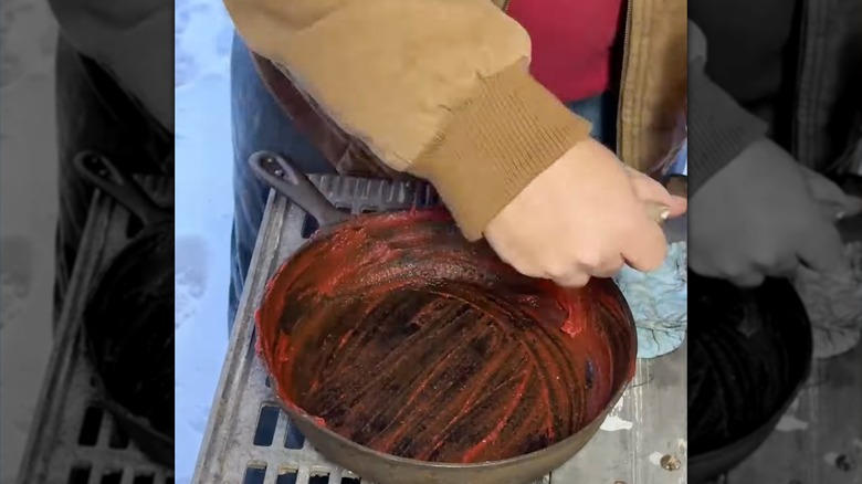 Man uses tomato paste to remove rust from iron skillet.