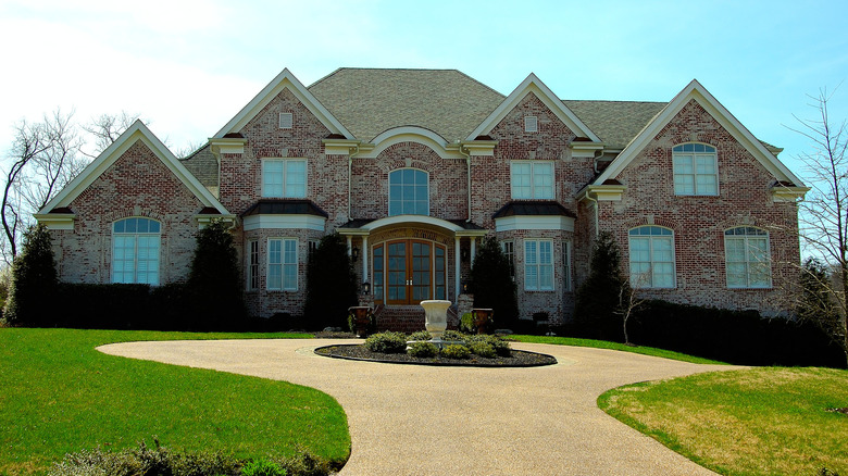 gravel driveway with a circular turnaround in front of a large brick house