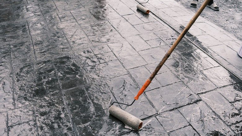 stamped concrete with a paint roller applying sealer