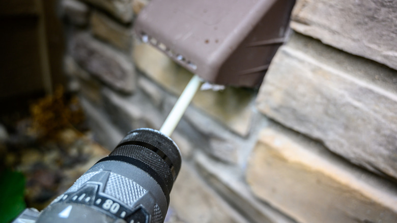 Close up of person using drill brush to clean dryer vent