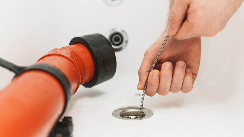 Close up of person using plumbing drain snake