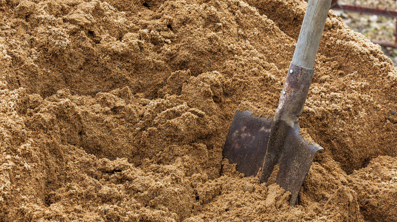 A shovel is placed in a large pile of sand