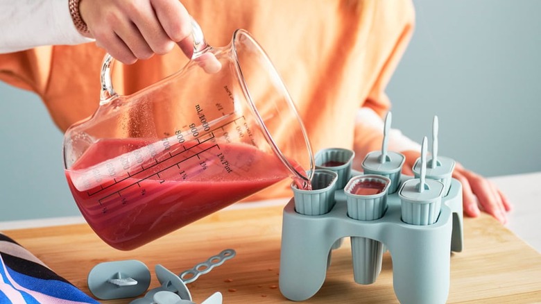 woman pour juice blend into popsicle mold