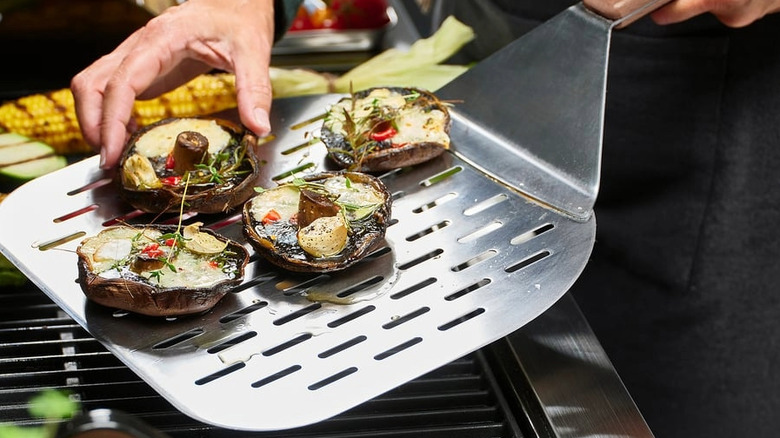 Someone moving stuffed mushrooms onto a pizza peel