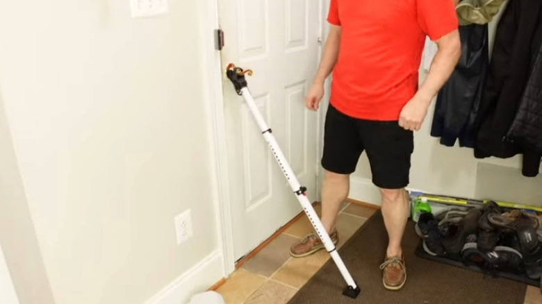A man stands next to door security bar fitted to a front door.