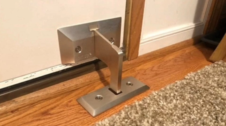 A metal floor barricade screwed into a front door and the floor.