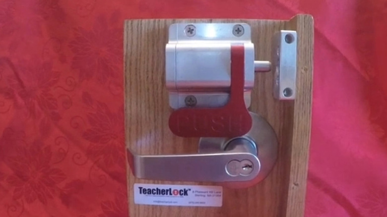 A TeacherLock mid-mount barricade installed on the inside of a red front door.