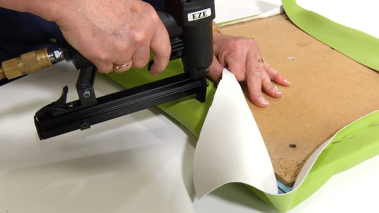Man reupholsters a chair seat with vinyl