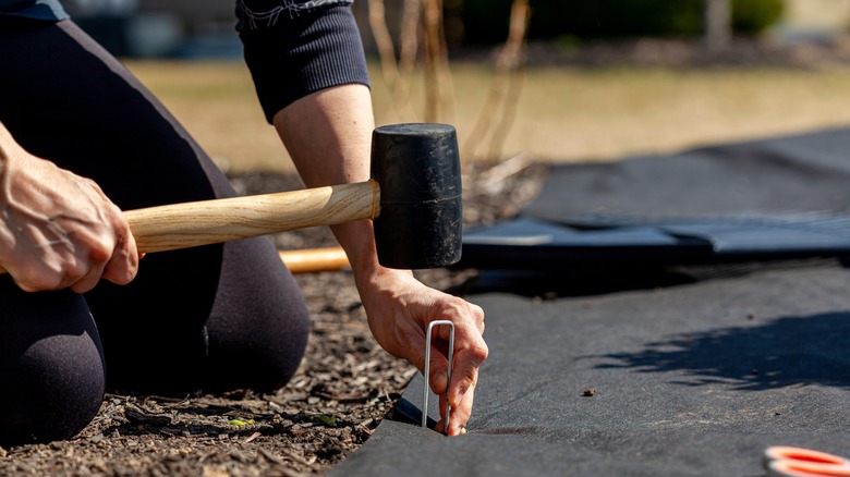 Installing landscaping fabric using mallet