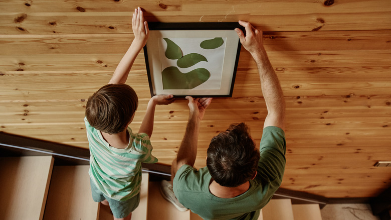 Dad and kid hanging a frame on the wall