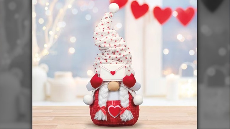 A stuffed gnome with a pointy hat holds a letter over its eyes