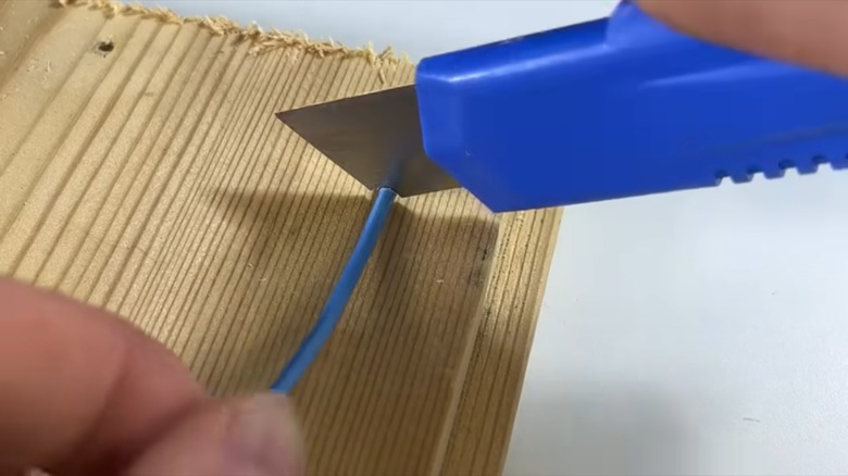 person stripping wire with boxcutter