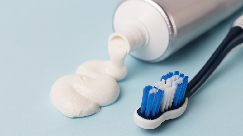 White toothpaste squeezed out onto a blue surface with a toothbrush next to it