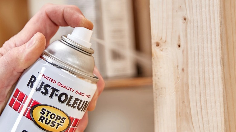 A person sprays sealant on a wooden surface