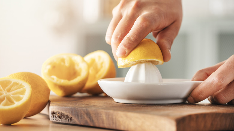 A person twists half a lemon onto a citrus juicer