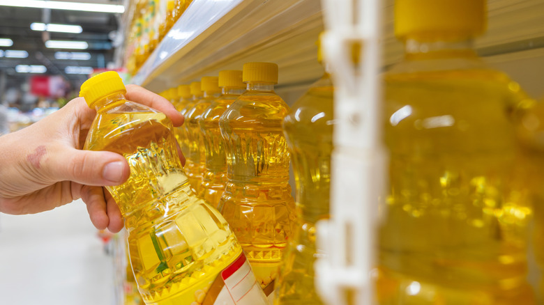 A shopper grabs a bottle of vegetable oil from a store shelf