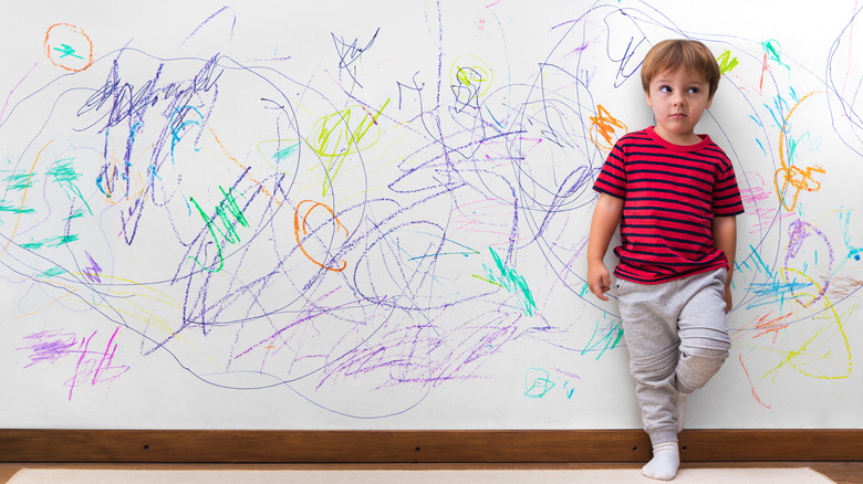 Boy and crayons on wall