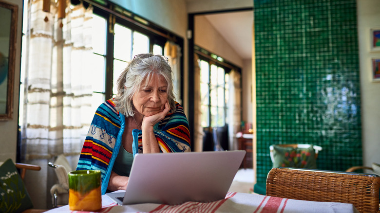 Older woman browsing laptop in decorated kitchen