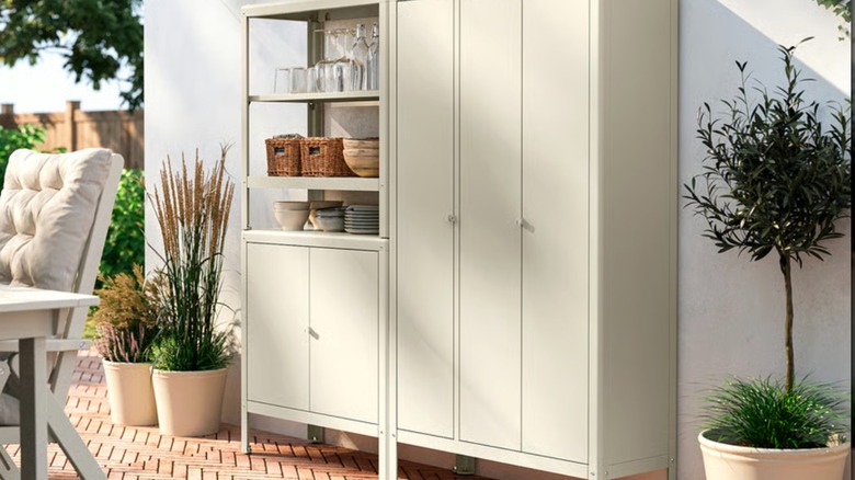 IKEA KOLBJÖRN Shelving unit on a patio with plant supplies and drinkware on the shelves.