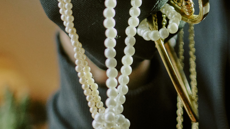 masked thief clutching a handful of jewelry