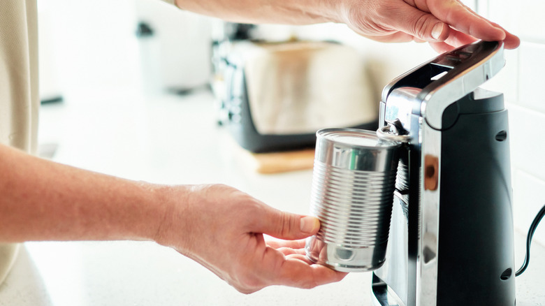 Man using an electric can opener on a plain can