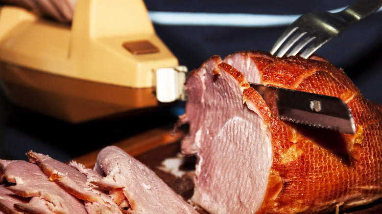 Electric knife cutting slices of ham