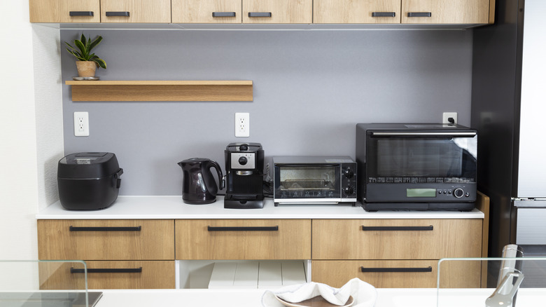 Kitchen with various small black appliances on the counter