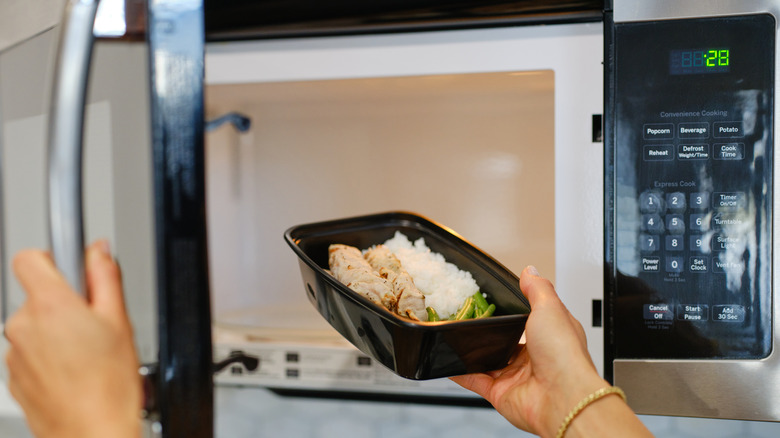 Hand putting leftover food in an over-the-stove microwave