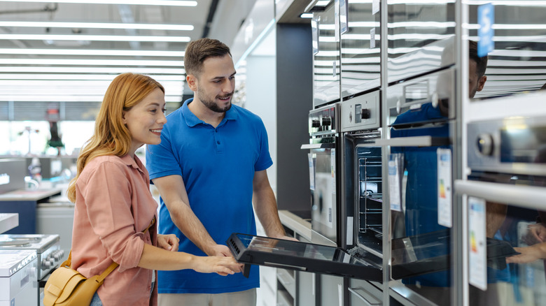 Man and woman inspecting an oven in a showroom.