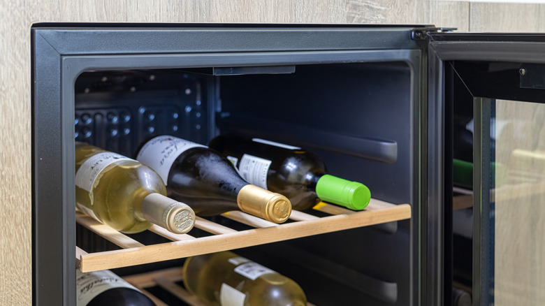 An open wine fridge with wine bottles arranged on the racks.