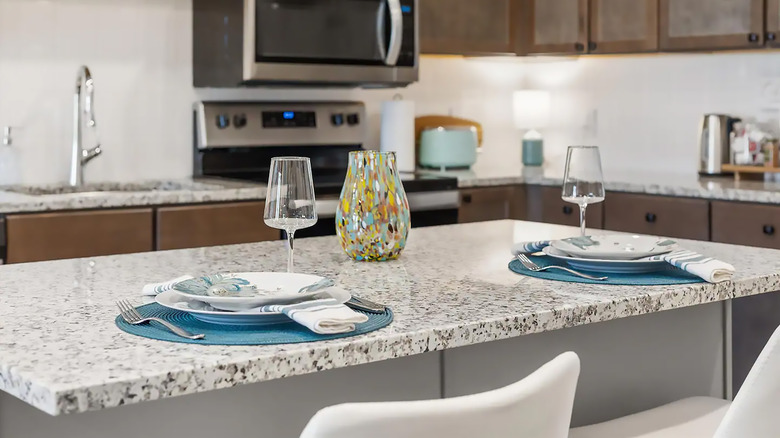 Dinner setup in an apartment kitchen with focus on speckled granite countertop.
