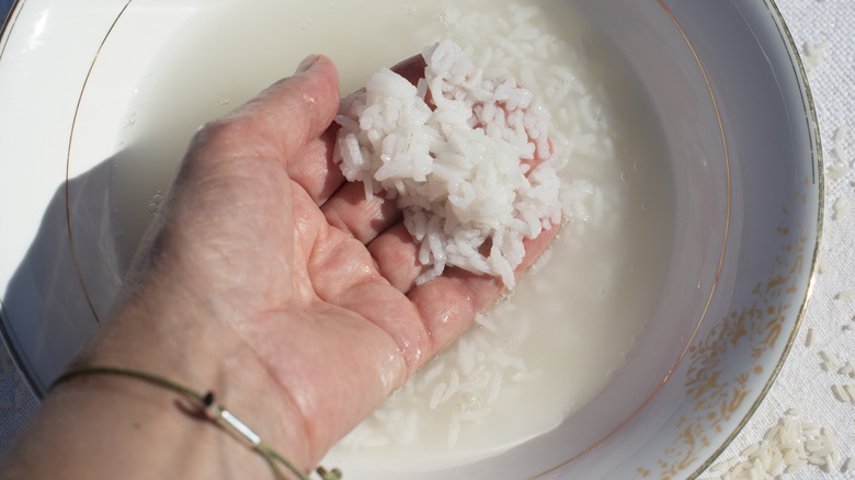 a woman rinsing rice in water