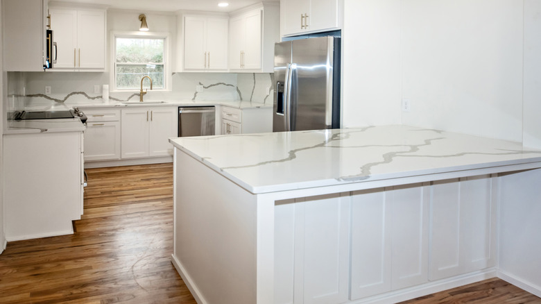 kitchen with white cabinets and counter and backsplash made of quartz tile