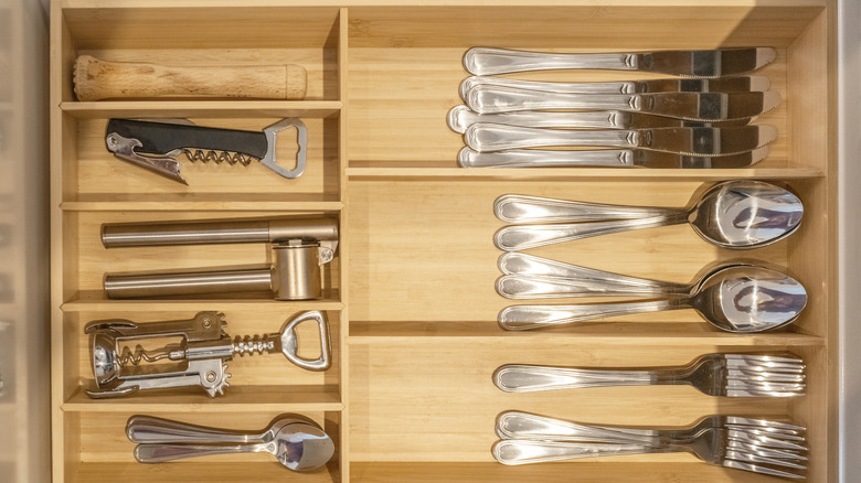 a drawer divider separating utensils into sections