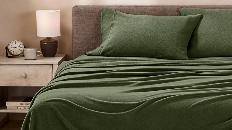 Bare Home green fleece sheets on a bed with a headboard, nightstand, and decor nearby