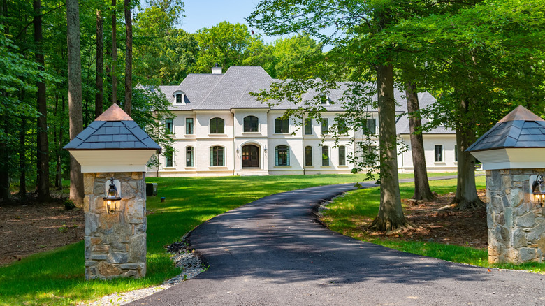 Asphalt driveway leading to large white house