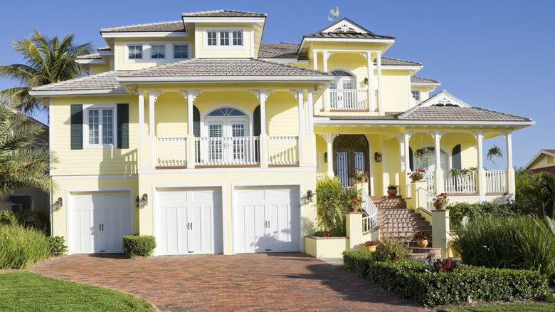 Large yellow house with brick driveway