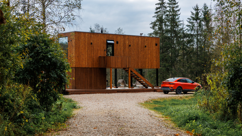 Gravel driveway leading to wooden house in the woods