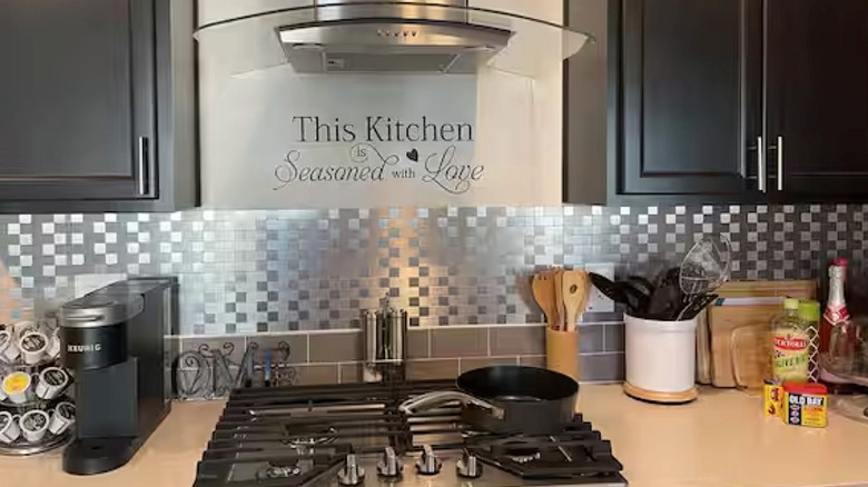 Aluminum mosaic backsplash over a gas range top and counter with kitchen items