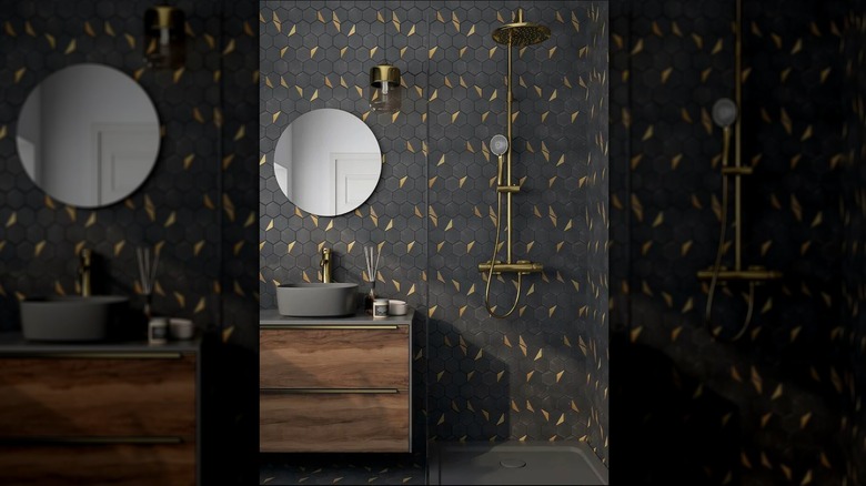 Modern bathroom with black hexagon tiles with brass accents and brass fixtures in the shower and vanity